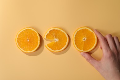 Woman with slices of juicy orange on beige background, top view