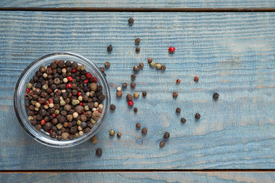 Photo of Mixed peppercorns in jar on blue wooden table, flat lay
