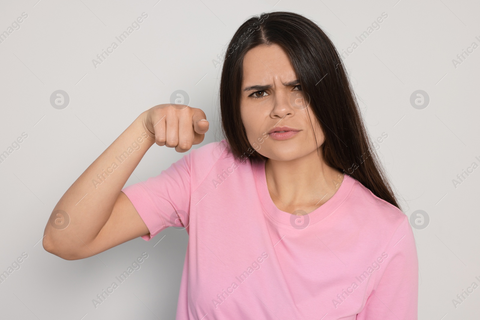 Photo of Aggressive young woman pointing on light grey background