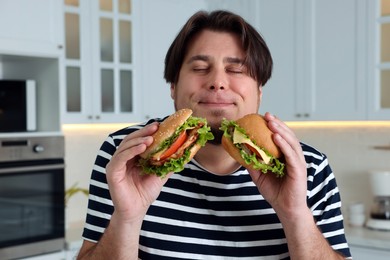 Photo of Happy overweight man tasty burgers in kitchen