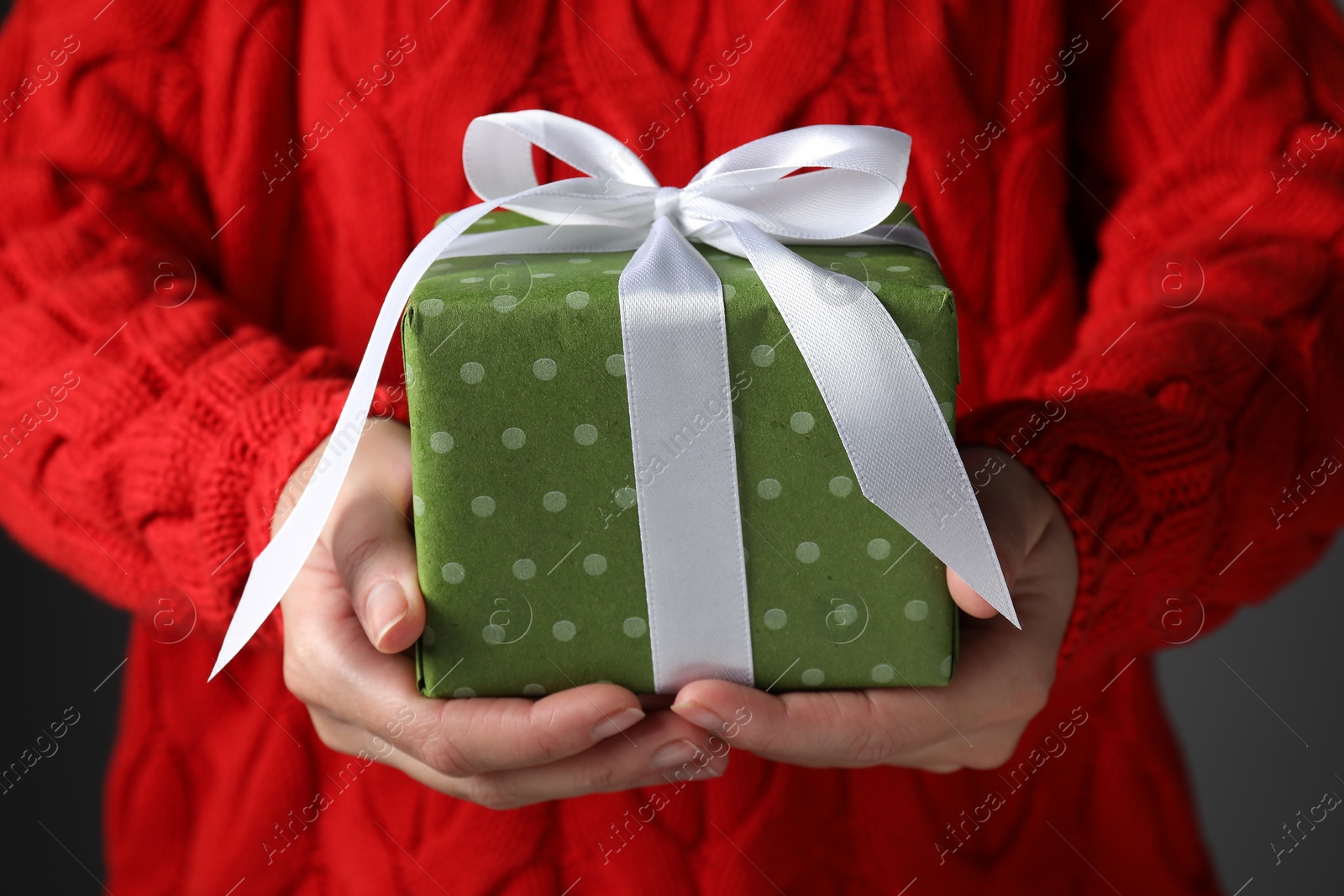 Photo of Christmas present. Woman holding gift box against grey background, closeup