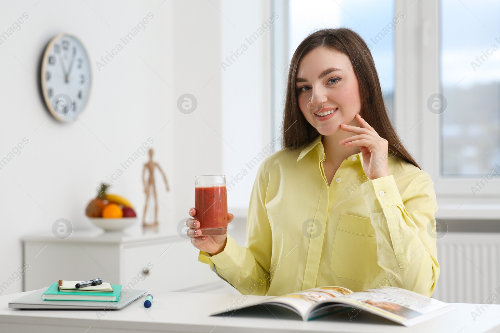 Photo of Beautiful young woman with delicious smoothie at table indoors