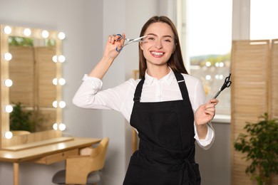 Portrait of happy hairdresser with professional scissors in beauty salon