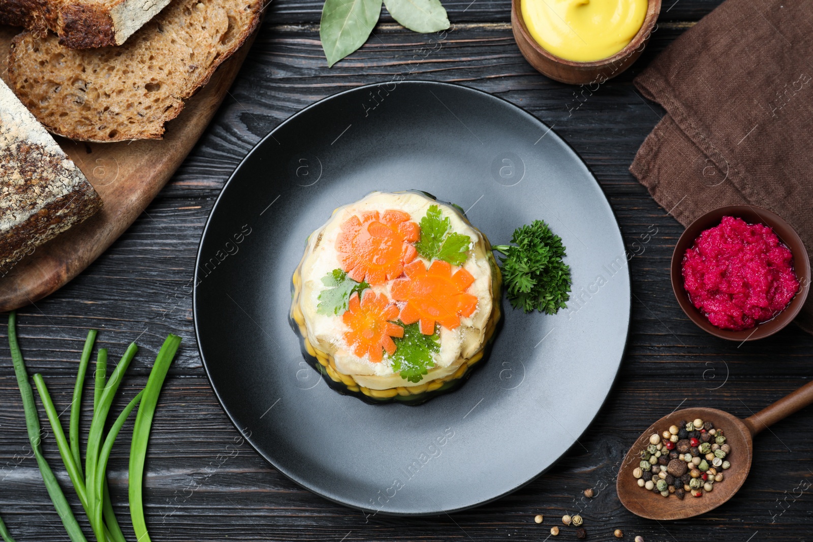 Photo of Delicious homemade chicken aspic served on black wooden table, flat lay