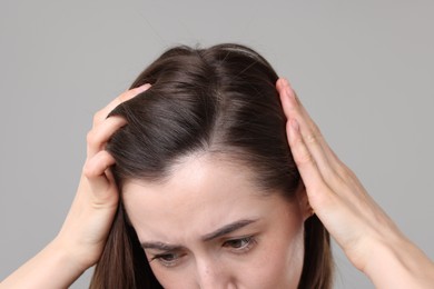 Sad woman with hair loss problem on grey background, closeup