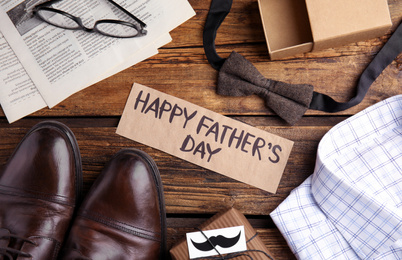 Photo of Flat lay composition with words HAPPY FATHER'S DAY and male accessories on wooden table