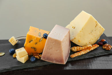 Different types of delicious cheeses on slate plate, closeup