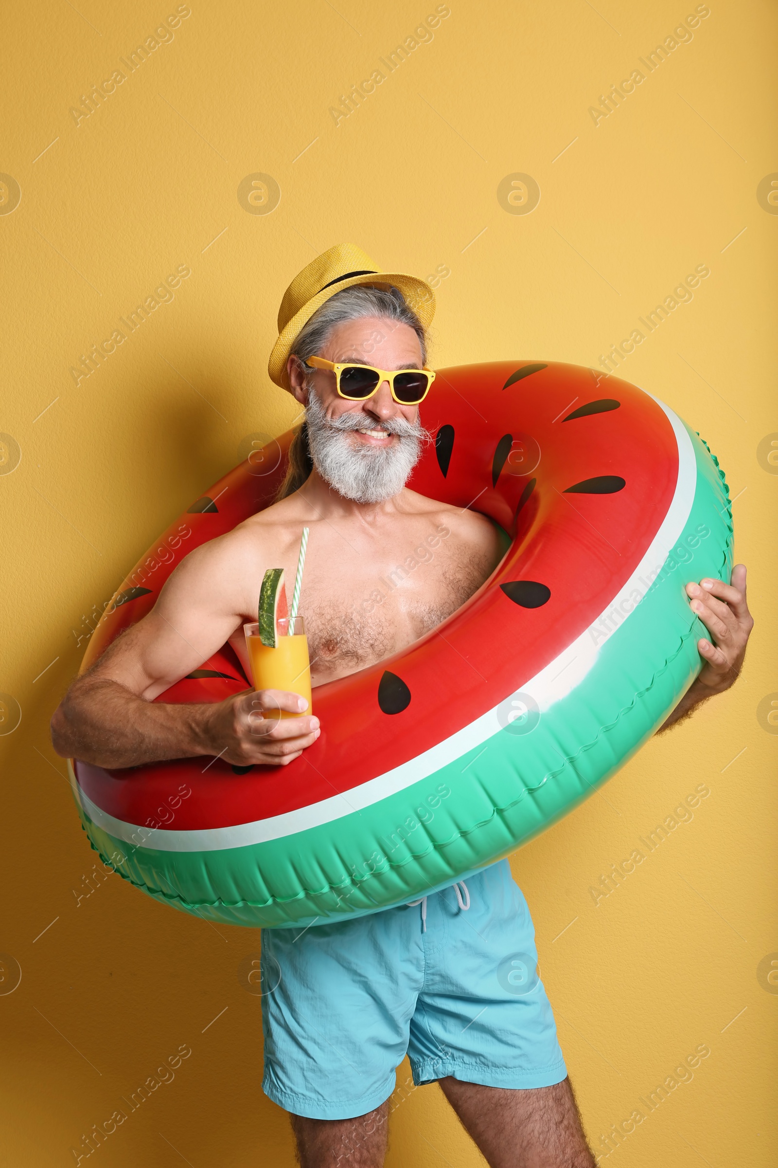 Photo of Shirtless man with inflatable ring and glass of cocktail on color background