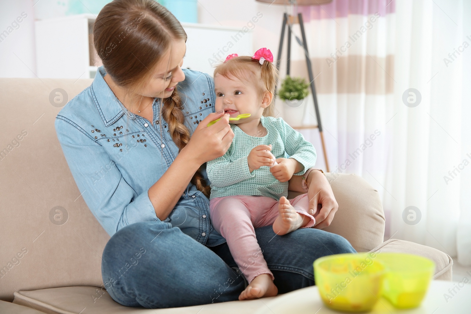 Photo of Caring mother feeding her cute little baby with healthy food at home