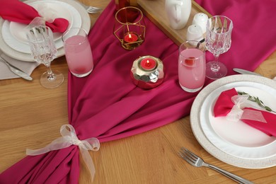 Photo of Color accent table setting. Glasses, plates, pink napkins and burning candles, above view