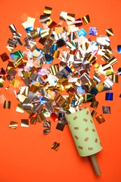 Photo of Party popper and colorful confetti on orange background, flat lay