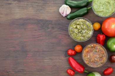 Photo of Tasty salsa sauces and ingredients on wooden table, flat lay. Space for text