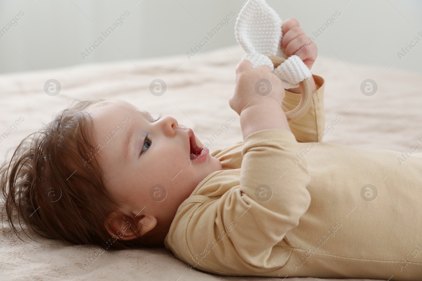 Photo of Cute little baby with toy on bed