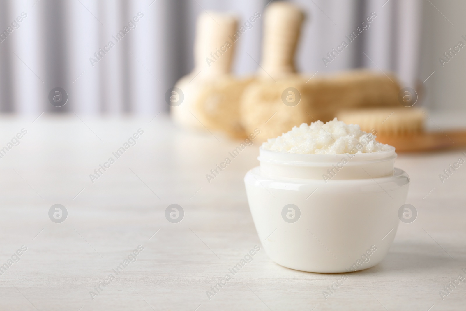 Photo of Jar of shea butter on table against blurred background. Space for text