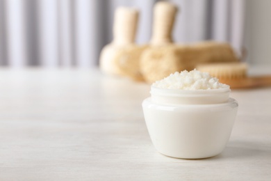 Jar of shea butter on table against blurred background. Space for text