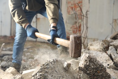 Photo of Man breaking stones with sledgehammer outdoors, closeup