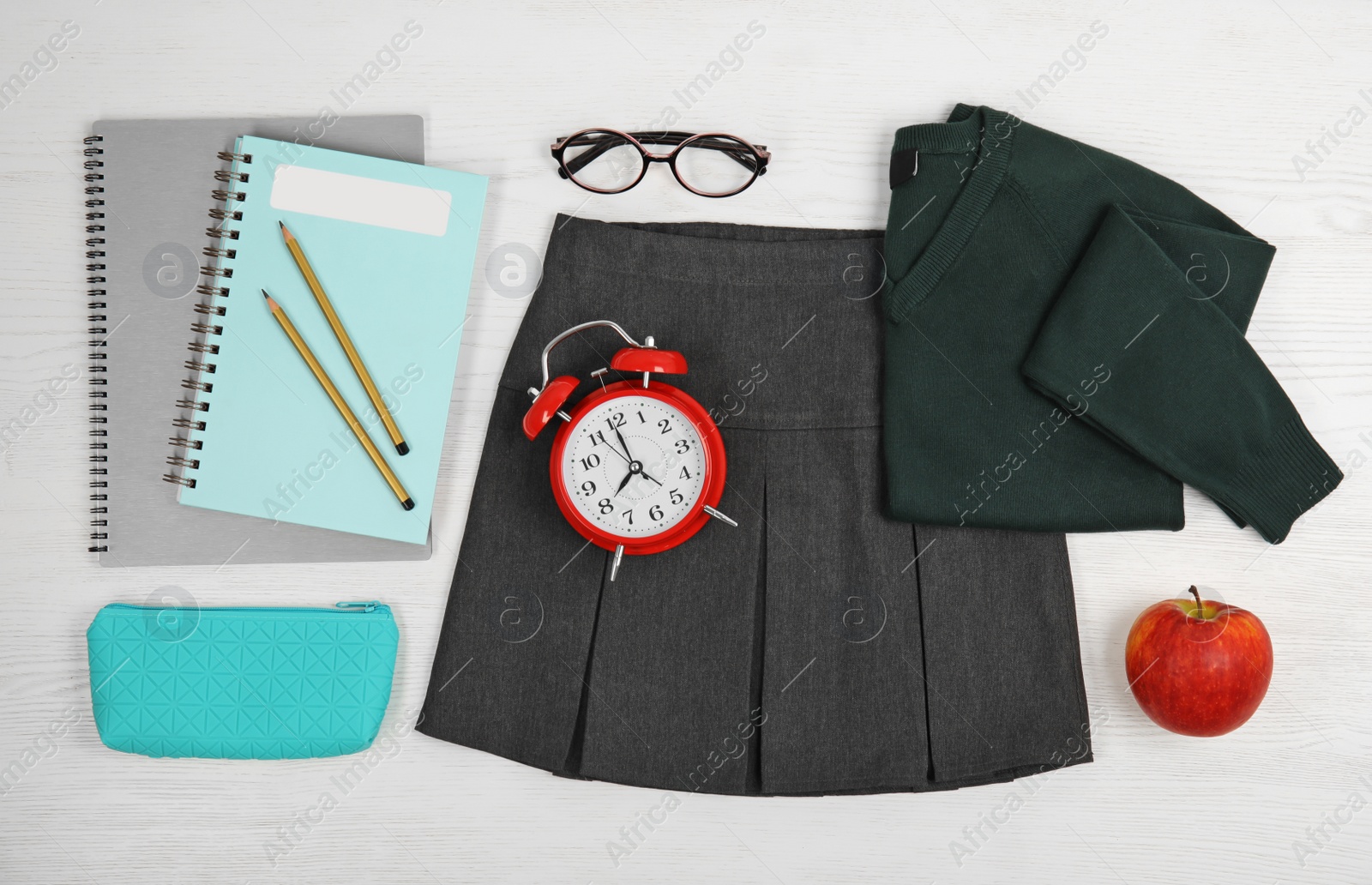 Photo of School uniform for girl and stationery on white wooden background, top view