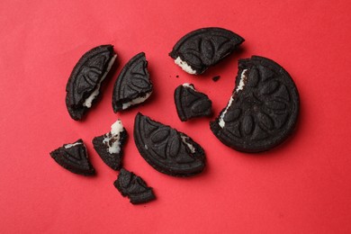 Photo of Pieces of tasty sweet sandwich cookies on red background, flat lay