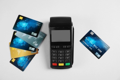 Modern payment terminal and credit cards on grey background, top view