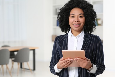 Photo of Smiling young businesswoman using tablet in office. Space for text