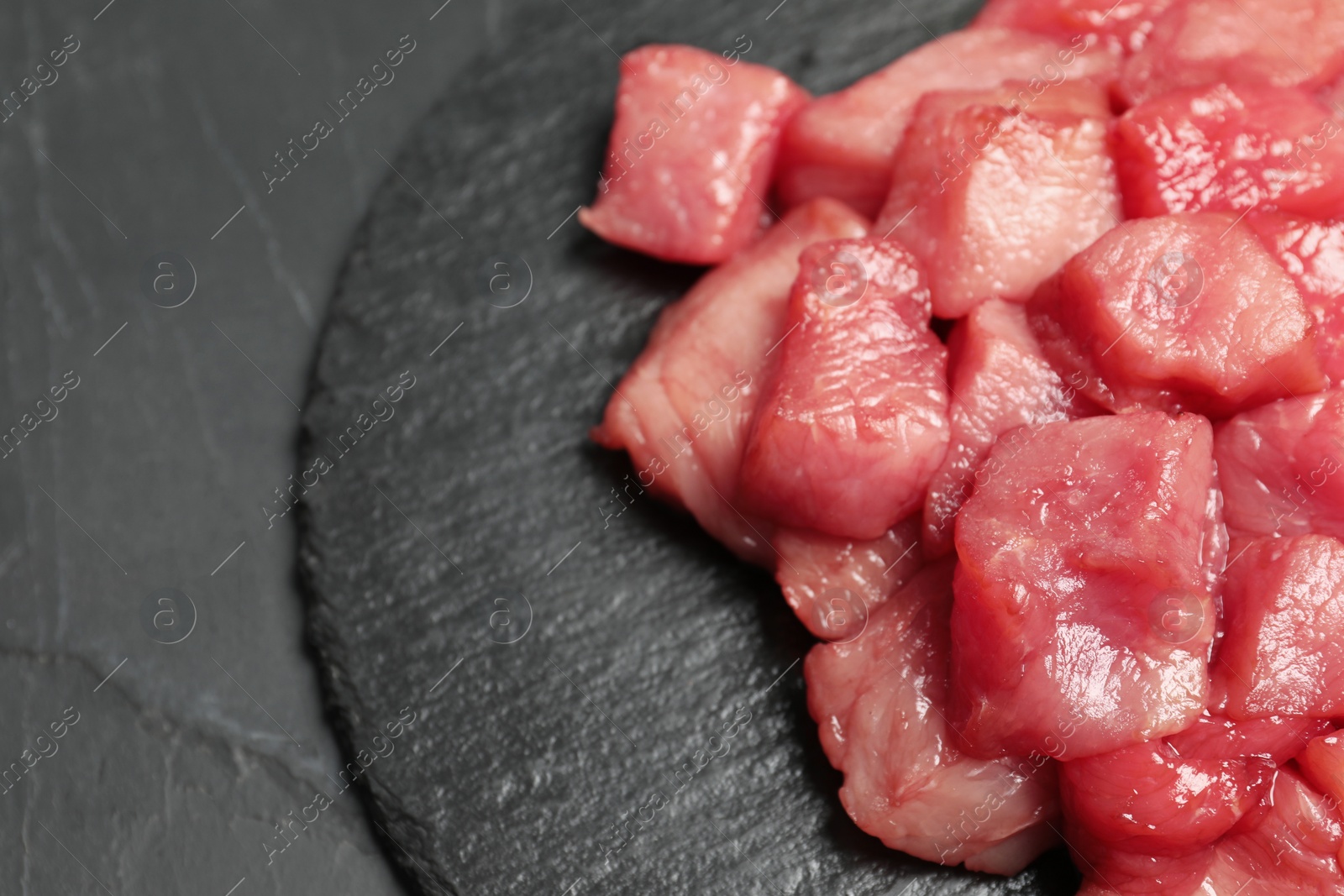 Photo of Cooking delicious goulash. Raw beef meat on black table, closeup with space for text