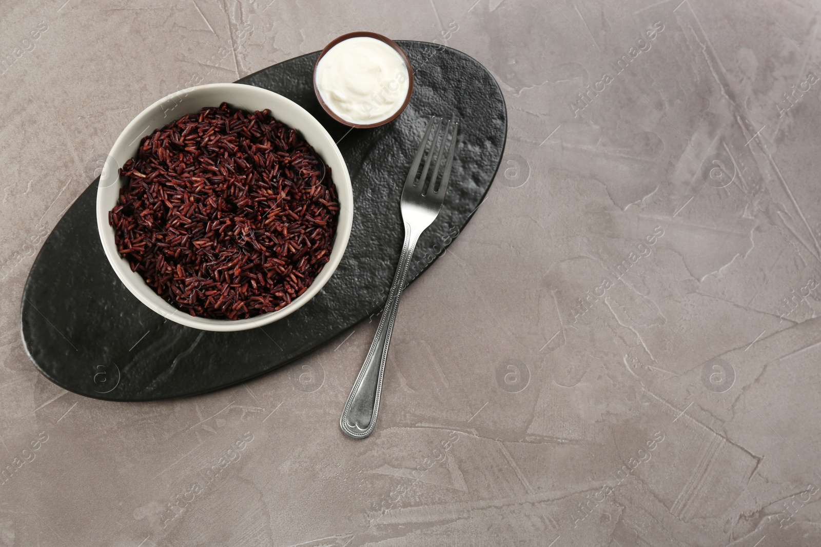 Photo of Tasty brown rice served on grey table, flat lay. Space for text