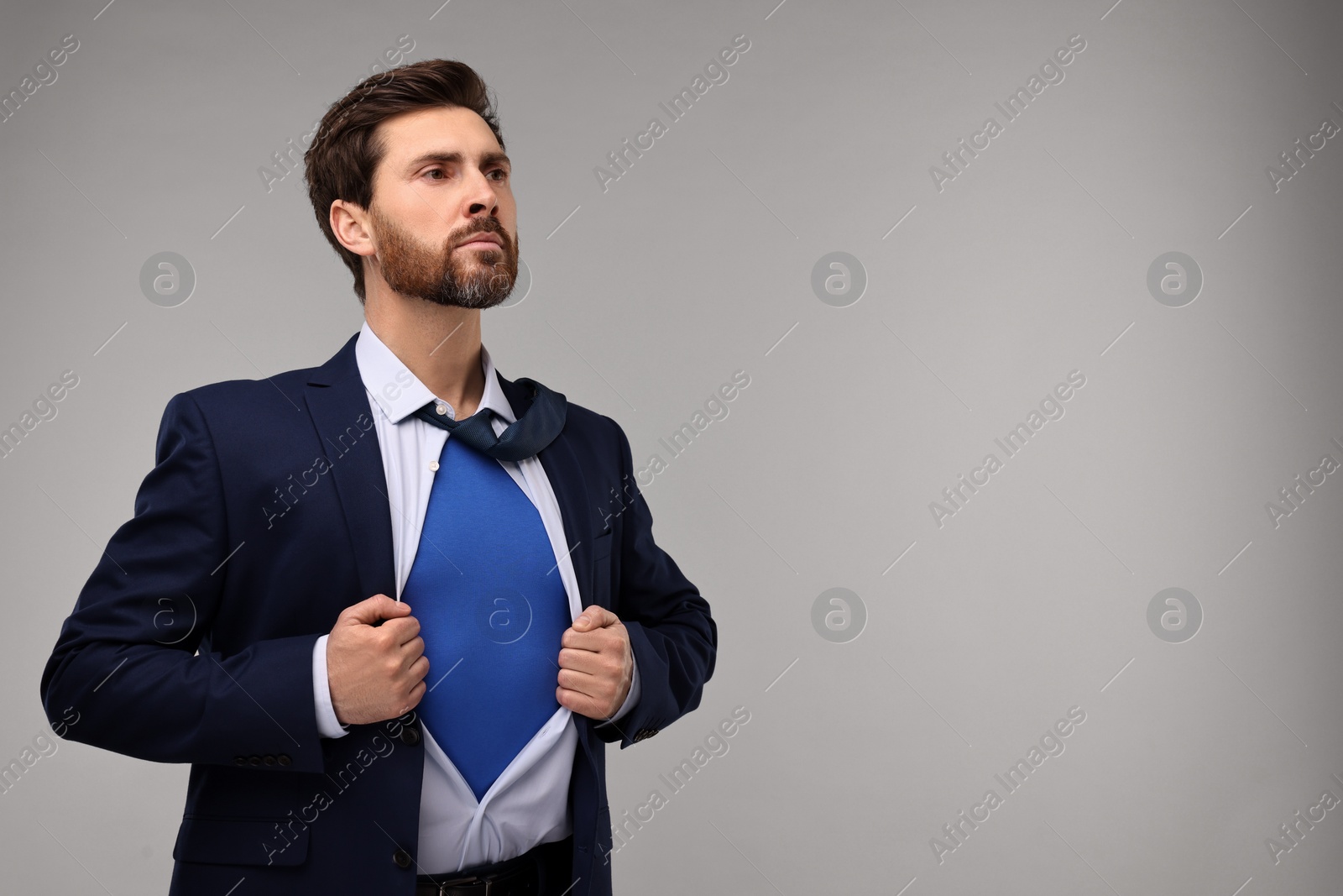 Photo of Confident businessman wearing superhero costume under suit on beige background. Space for text