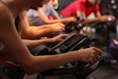 Photo of Group of people training on exercise bikes in fitness club, closeup