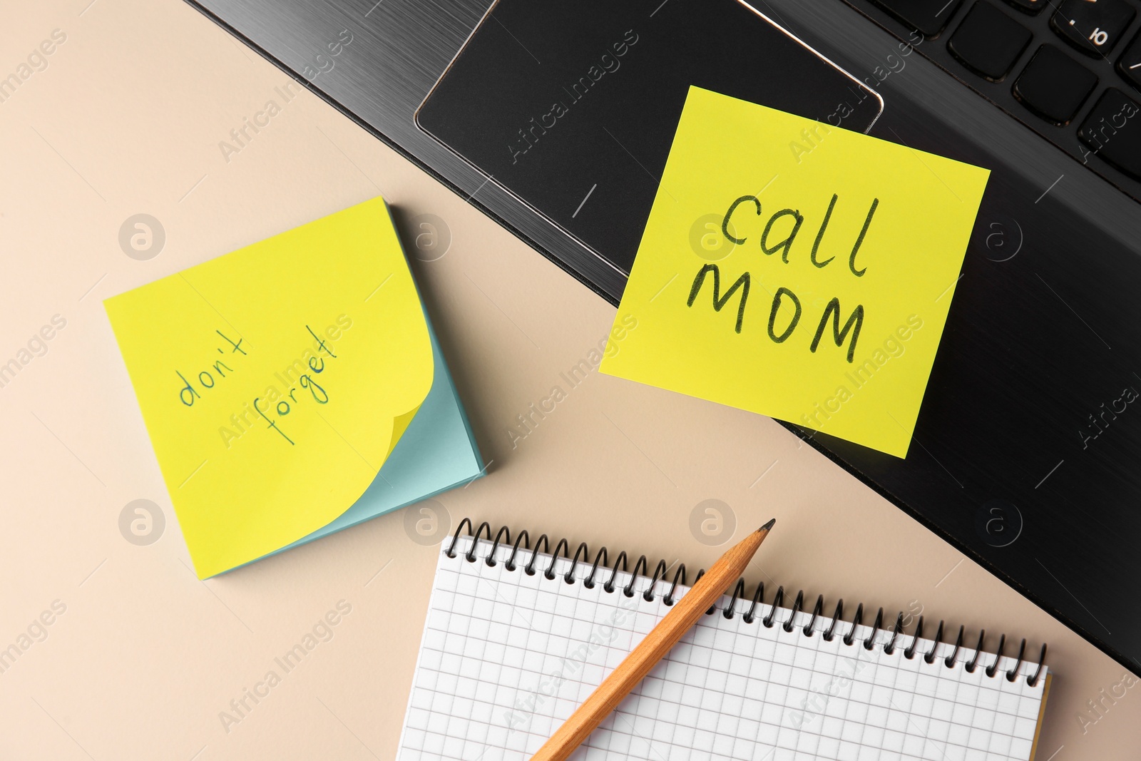 Photo of Paper notes with reminders, notebook and laptop on beige table, flat lay