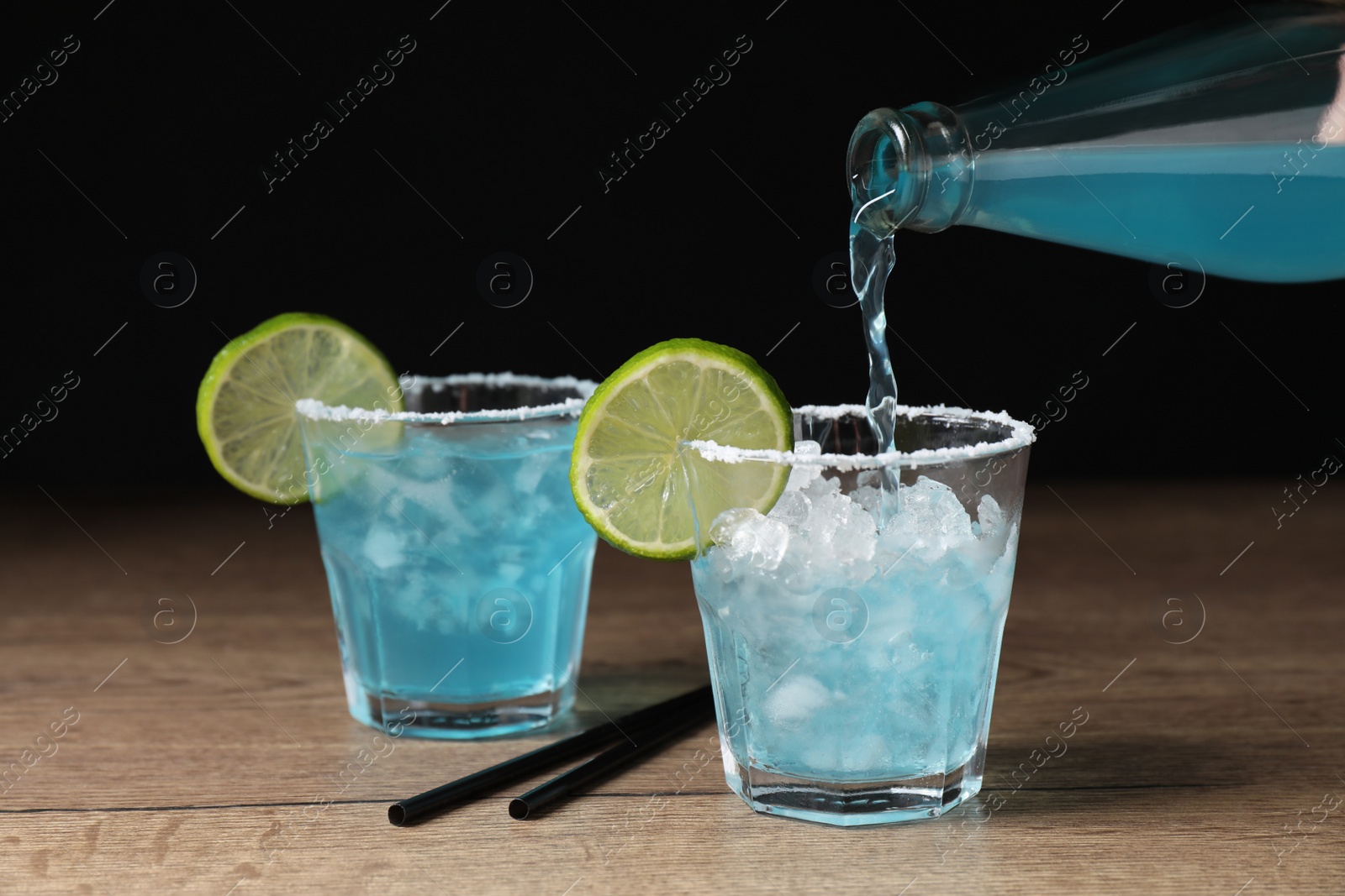 Photo of Pouring light blue drink into glass on wooden table