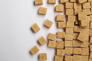 Photo of Brown sugar cubes on white background, flat lay. Space for text
