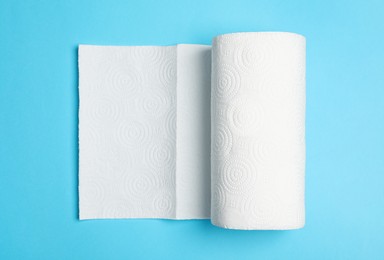 Photo of Roll of white paper towels on light blue background, top view