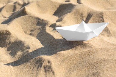 Photo of One white paper boat on sandy beach, space for text