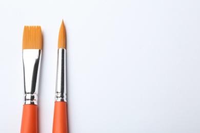 Photo of Different paint brushes on white background, top view. Space for text