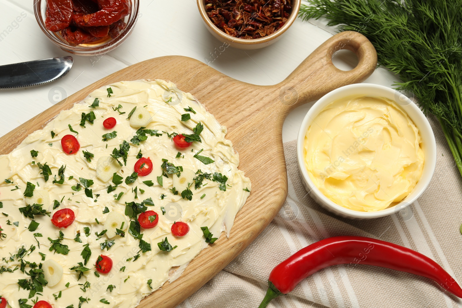 Photo of Fresh natural butter board with pepper, sun-dried tomatoes and dill on white wooden table, flat lay