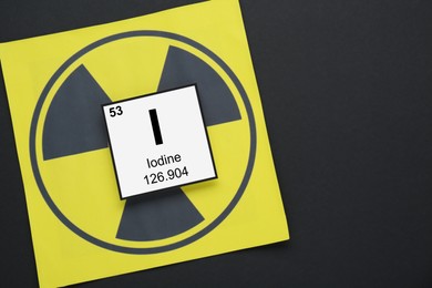 Card with chemical element Iodine and radiation sign on black background, top view. Space for text