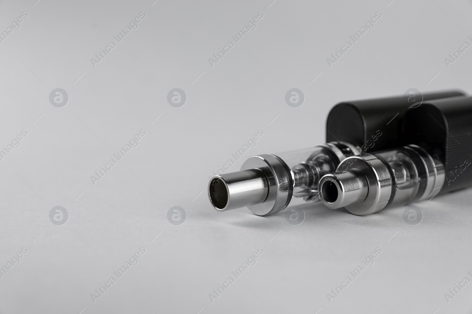 Photo of Two electronic cigarettes on light background, closeup. Space for text