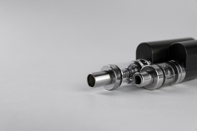 Photo of Two electronic cigarettes on light background, closeup. Space for text