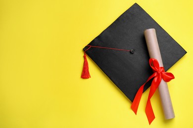 Photo of Graduation hat and diploma on yellow background, flat lay. Space for text