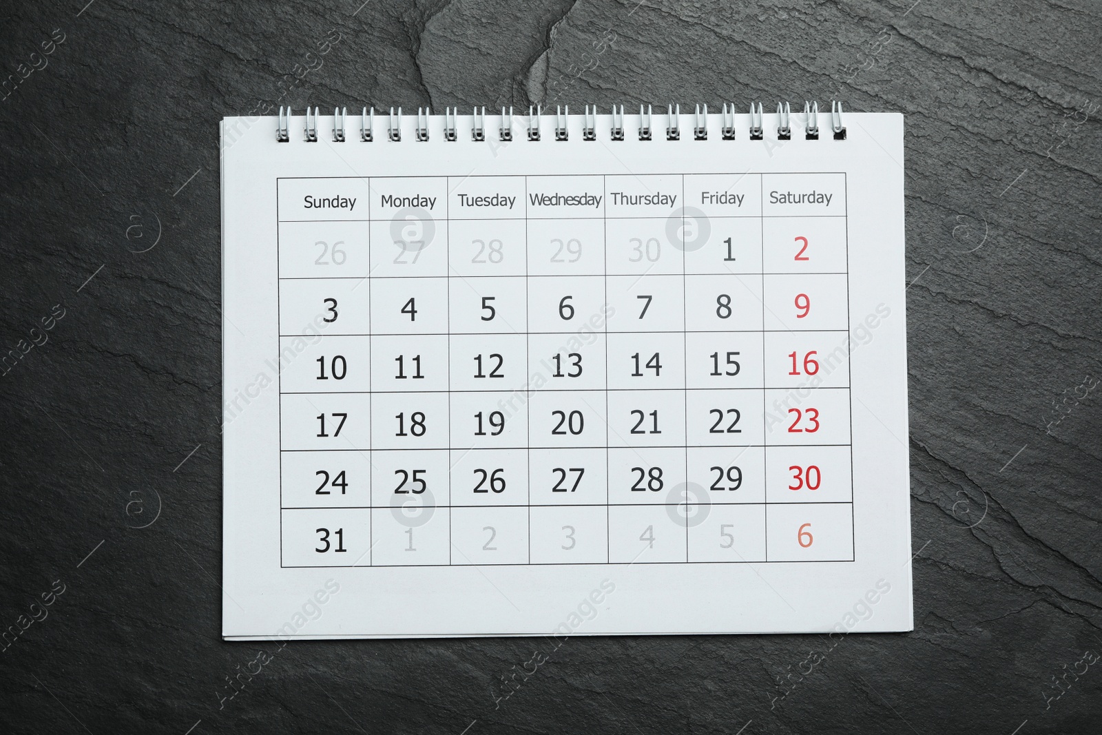 Photo of Paper calendar on black stone background, top view