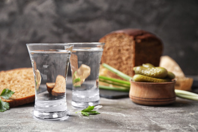 Photo of Cold Russian vodka with snacks on grey table, closeup