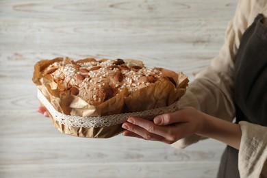 Photo of Woman with delicious Italian Easter dove cake (traditional Colomba di Pasqua) near white wooden wall, closeup