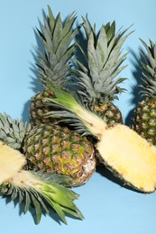 Whole and cut ripe pineapples on light blue background