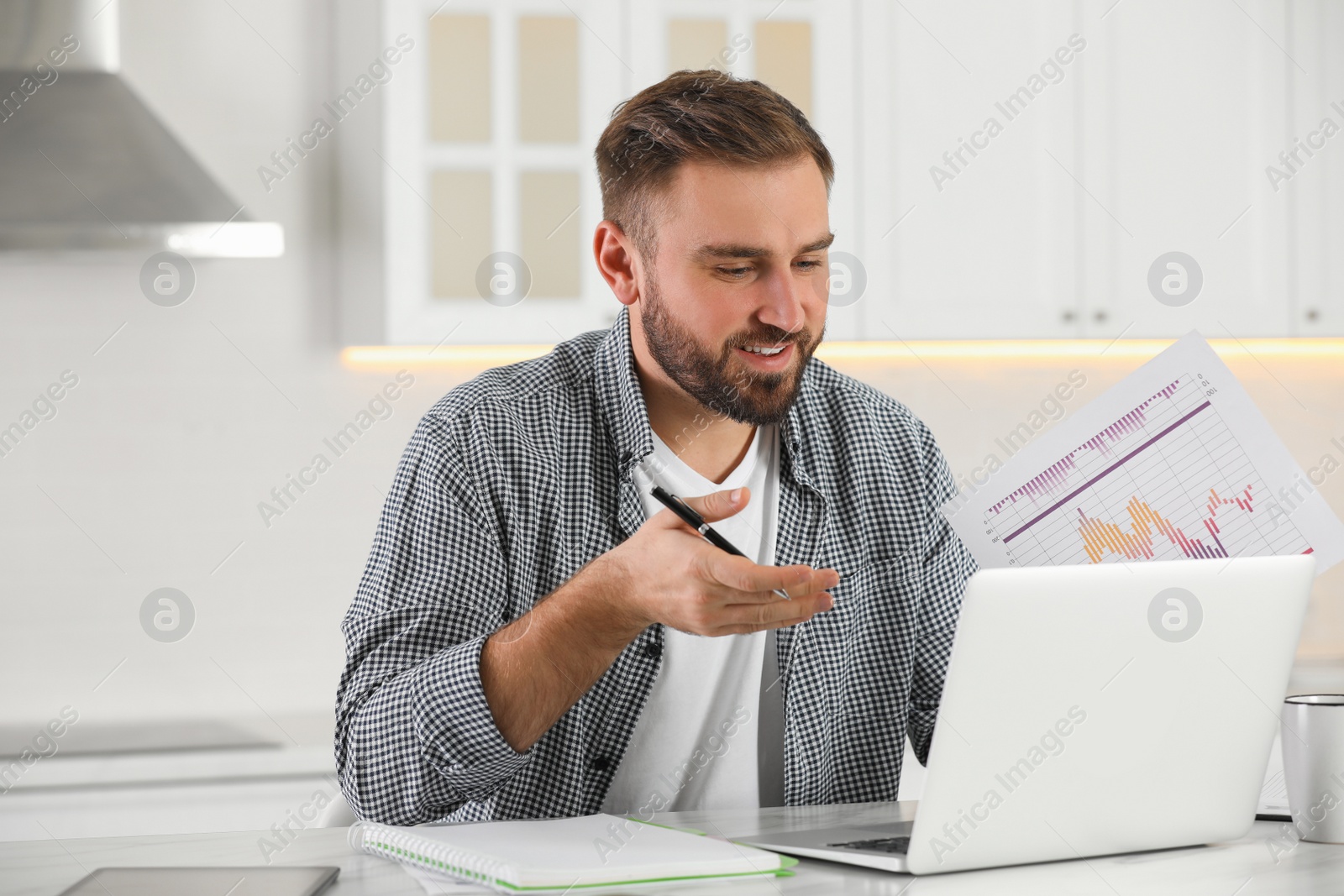 Photo of Young man having video call on laptop in kitchen. Working from home