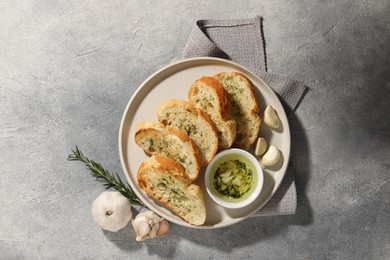 Photo of Tasty baguette with garlic and dill served on grey textured table, top view