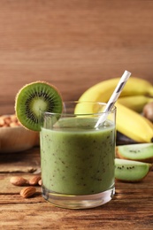 Photo of Delicious kiwi smoothie and ingredients on wooden table