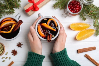 Photo of Woman with cup of aromatic mulled wine at white wooden table, closeup