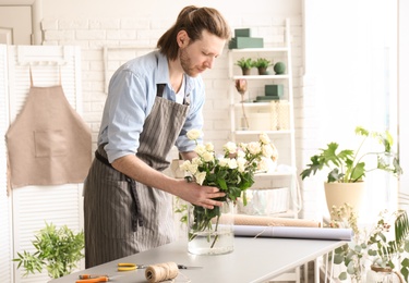 Photo of Male florist creating floral composition at workplace