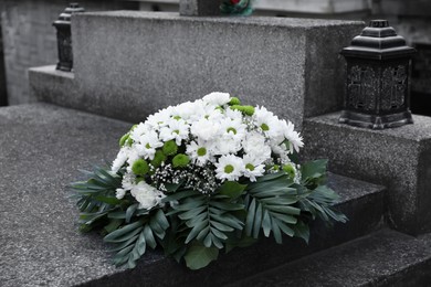 Photo of Funeral wreath of flowers on granite tombstone outdoors
