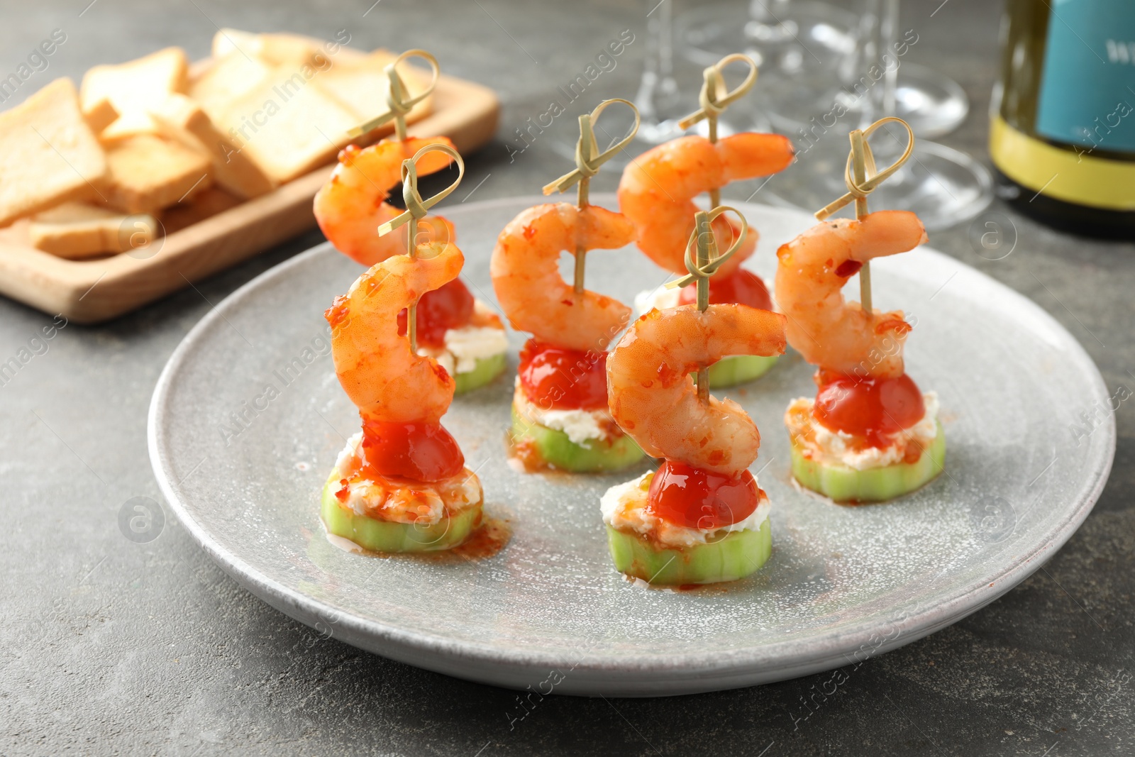Photo of Tasty canapes with shrimps, vegetables and cream cheese on grey table, closeup